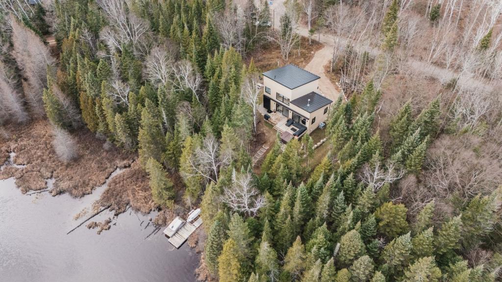 Séduisante propriété surplombant les eaux calmes d'un lac au milieu de la forêt