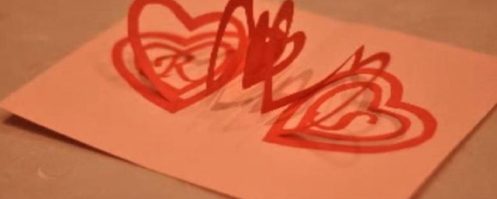 Il découpe une spirale dans un carton rouge pour faire la plus géniale des cartes POP-UP pour la Saint-Valentin :)