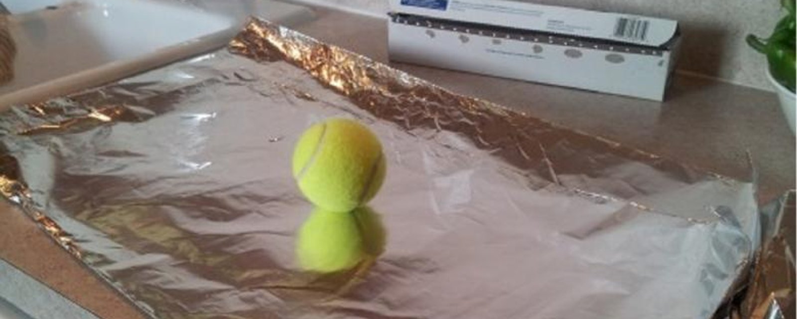 Avec un balle de tennis et du papier aluminium, elle remplace un article de maison coûteux! C'est brillant! 