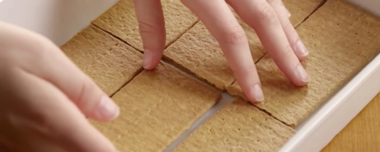 Elle étale des biscuits Graham dans un plat et nous montre comment créer un gâteau éclair en un temps record