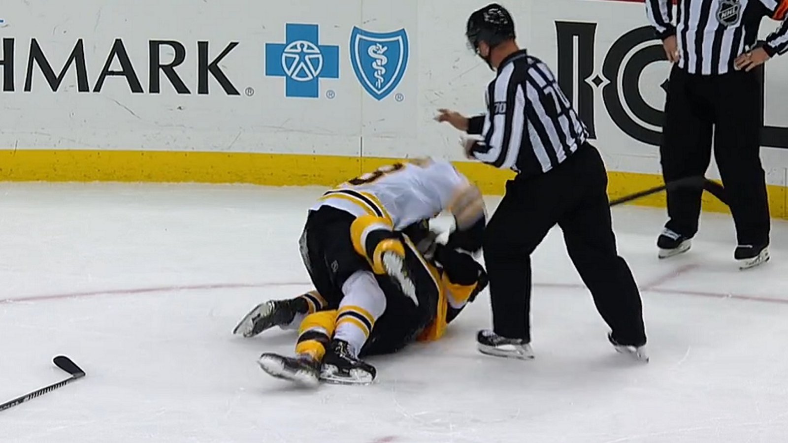 Brad Marchand and Kris Letang rough each other up behind the play.