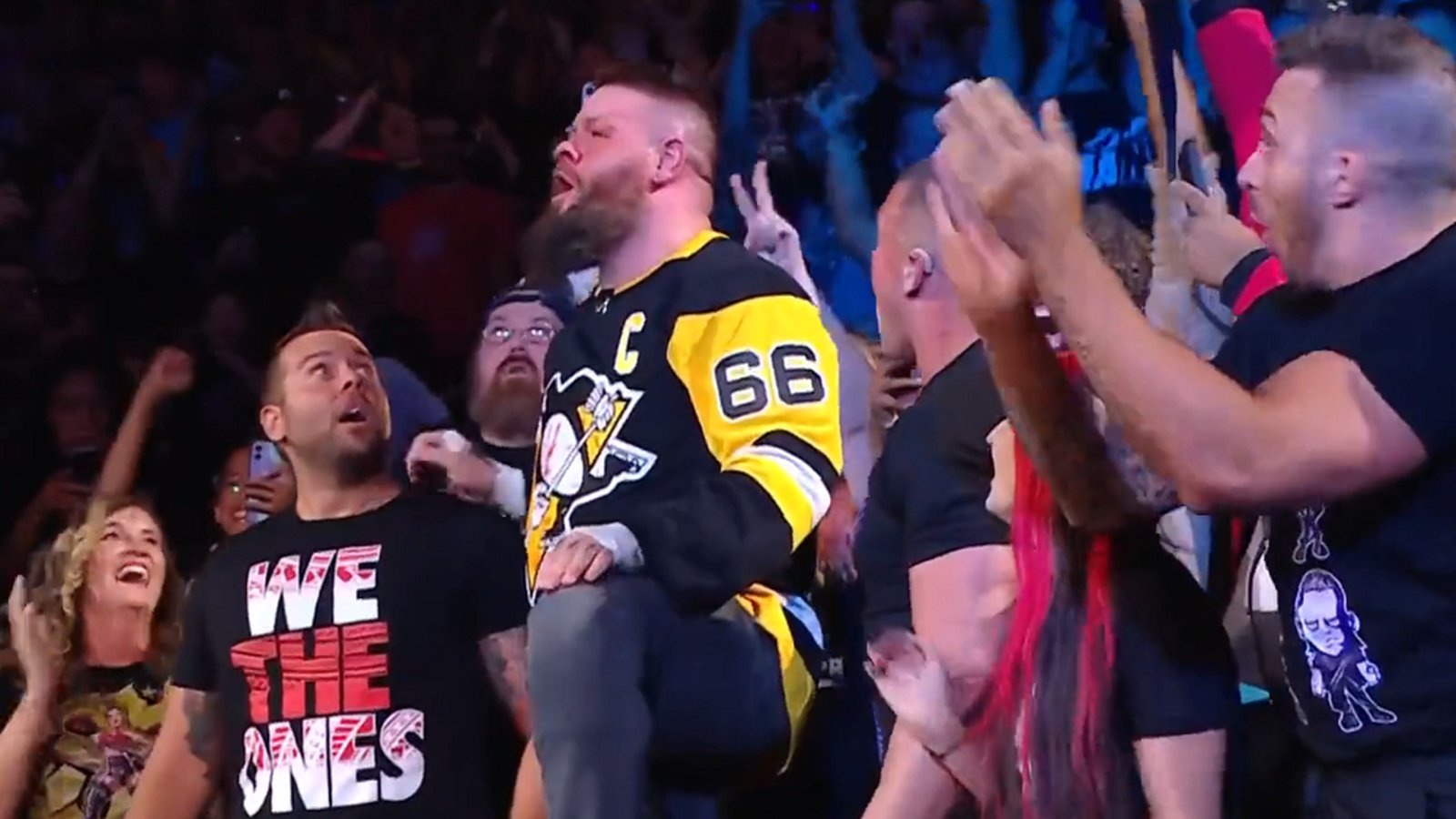 Kevin Owens jumps off railing wearing Mario Lemieux jersey.