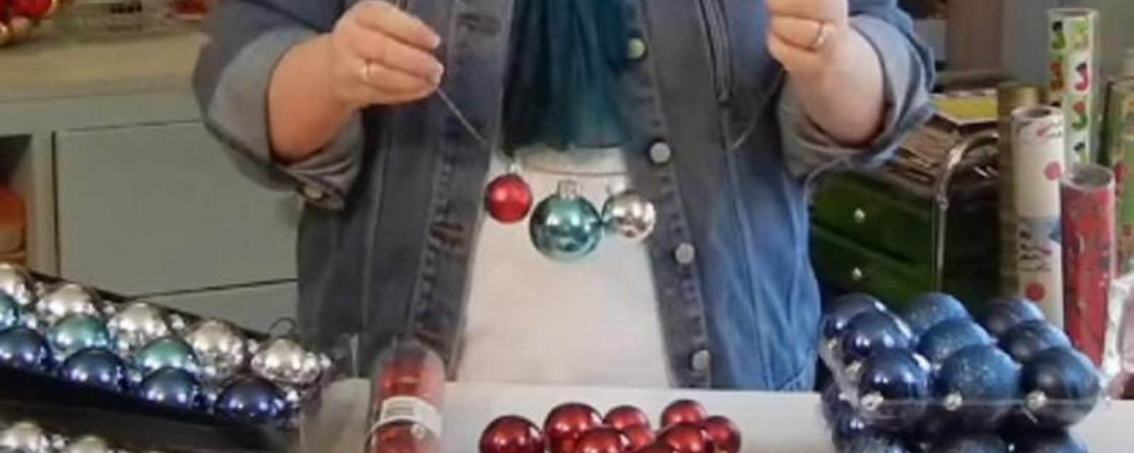 Elle enfile des boules de Noël sur un support de métal afin de créer une superbe décoration de Noël