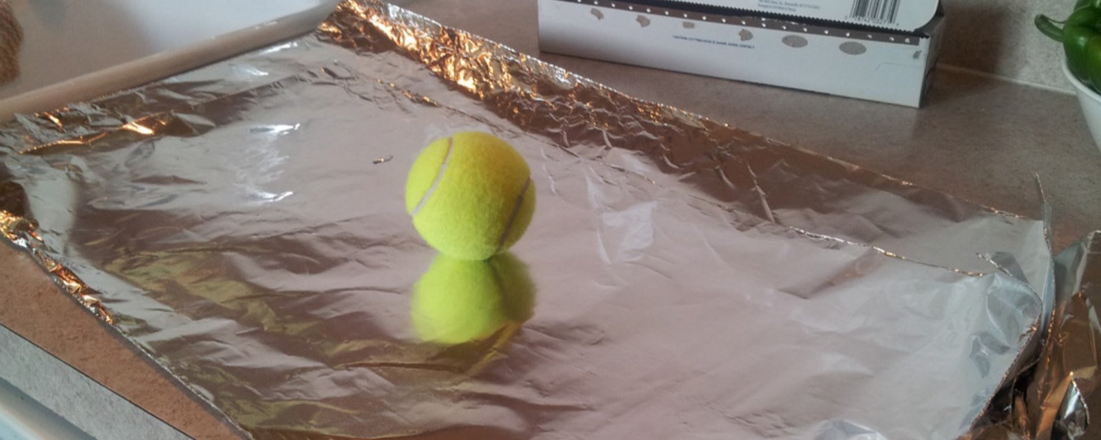 Elle enveloppe une balle de tennis avec du papier d’aluminium et la met dans la sécheuse