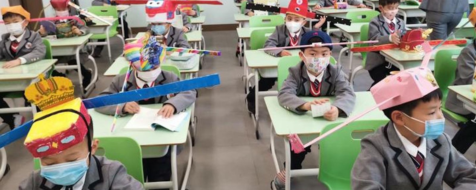 Déconfinement: des enfants chinois retournent à l’école en portant des chapeaux de distanciation sociale