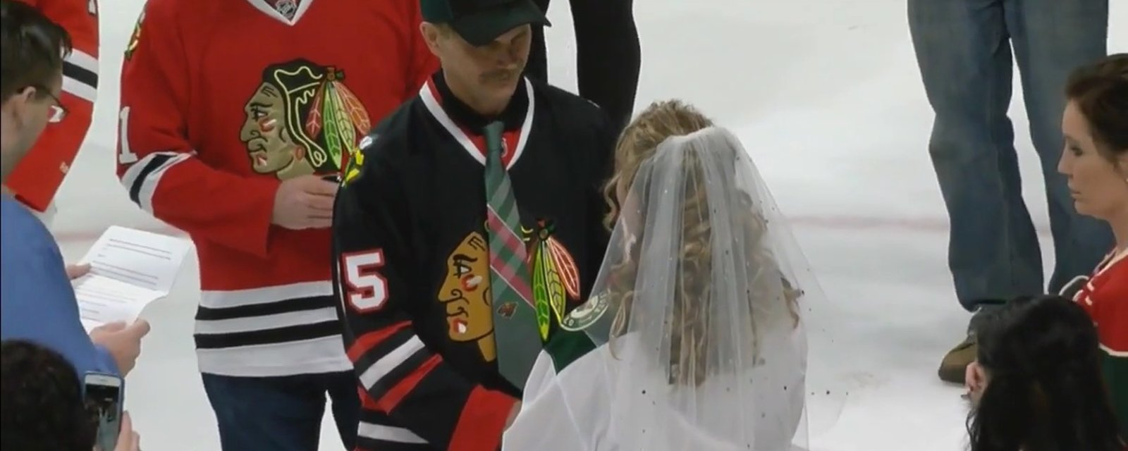 Wild fan marries a Blackhawks' fan on ice prior to puck drop.