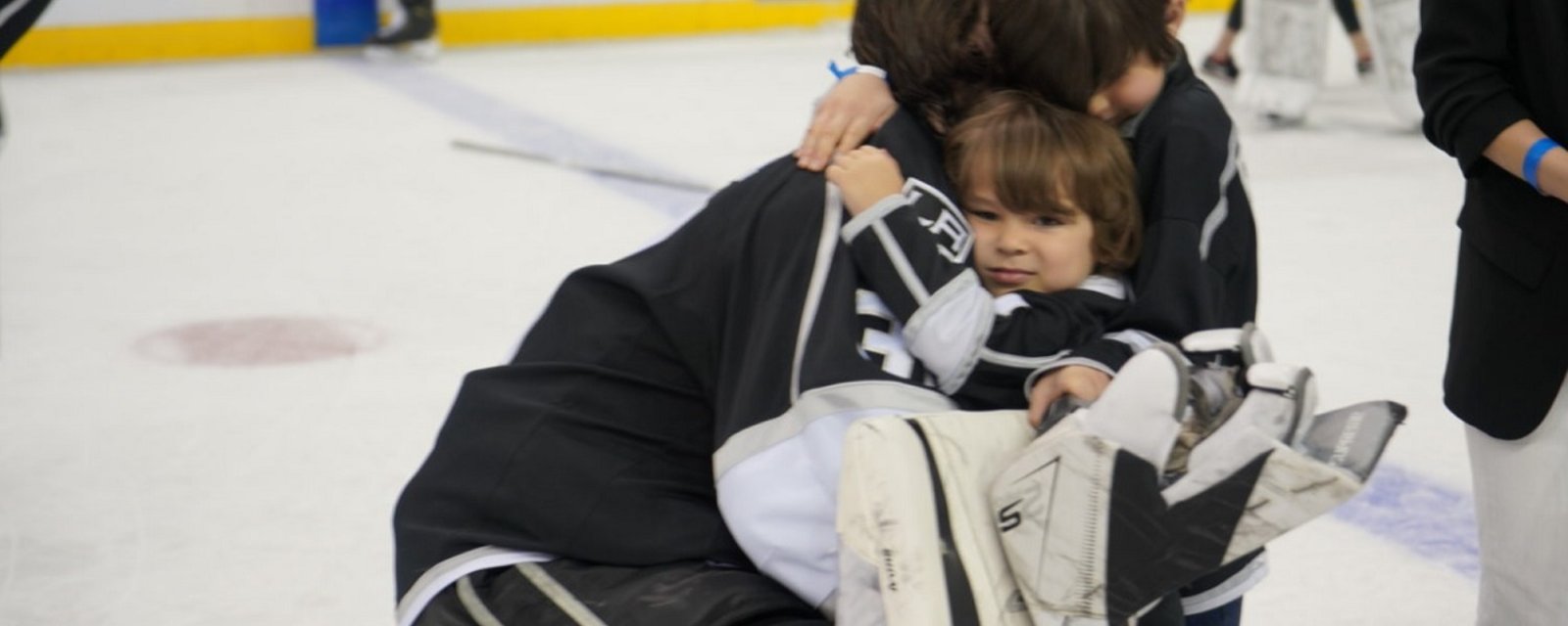 NHL goalie embraced by his family on the ice after what is likely his final game.