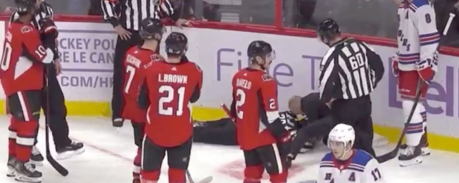 Referee falls on the ice after getting puck to the head