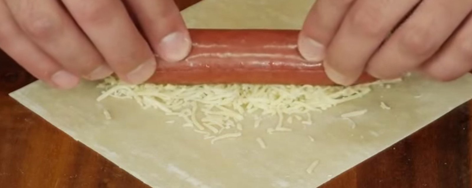 Il dépose des saucisses sur une pâte à egg roll et il crée un plat nouveau genre