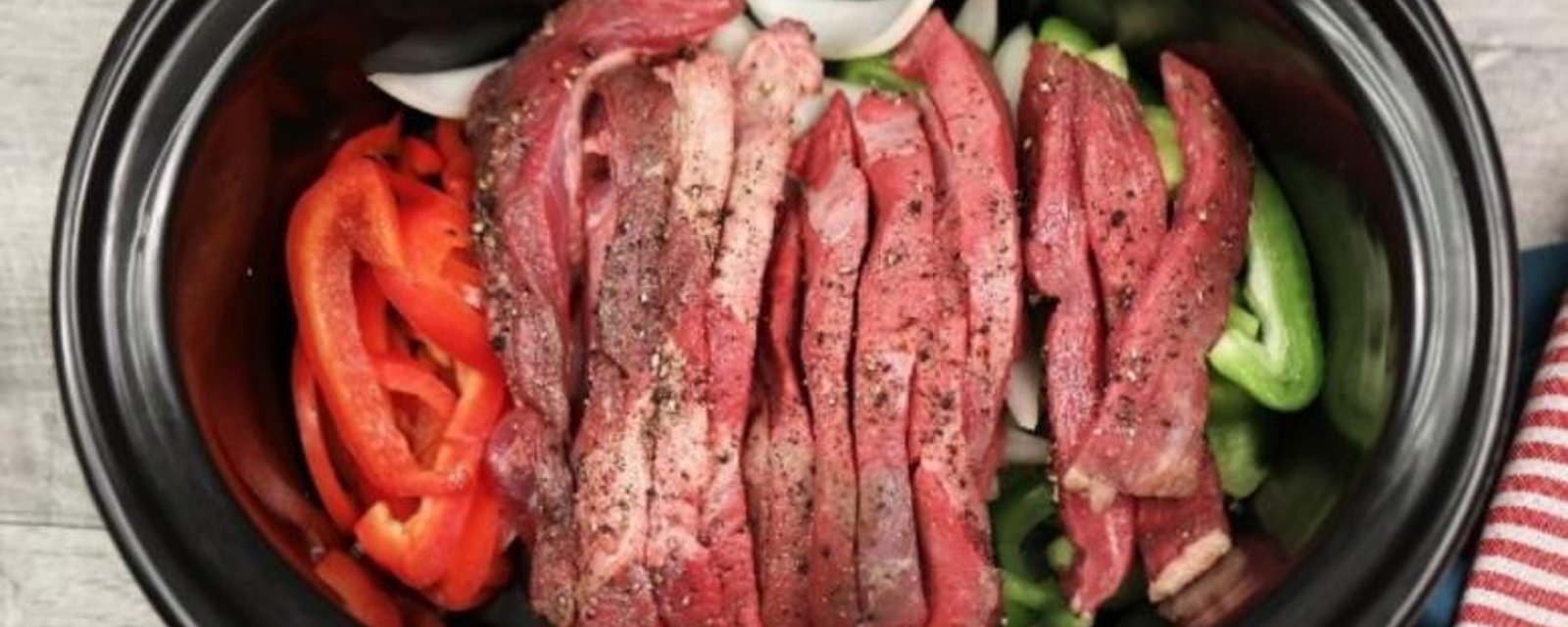 Elle met des oignons, des poivrons et des lanières de boeuf dans sa mijoteuse afin de créer le meilleur pepper steak 