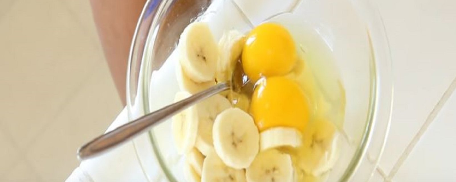 Dans un petit bol, elle casse un oeuf pour ensuite y ajouter des morceaux de banane afin de créer un déjeuner vraiment délicieux