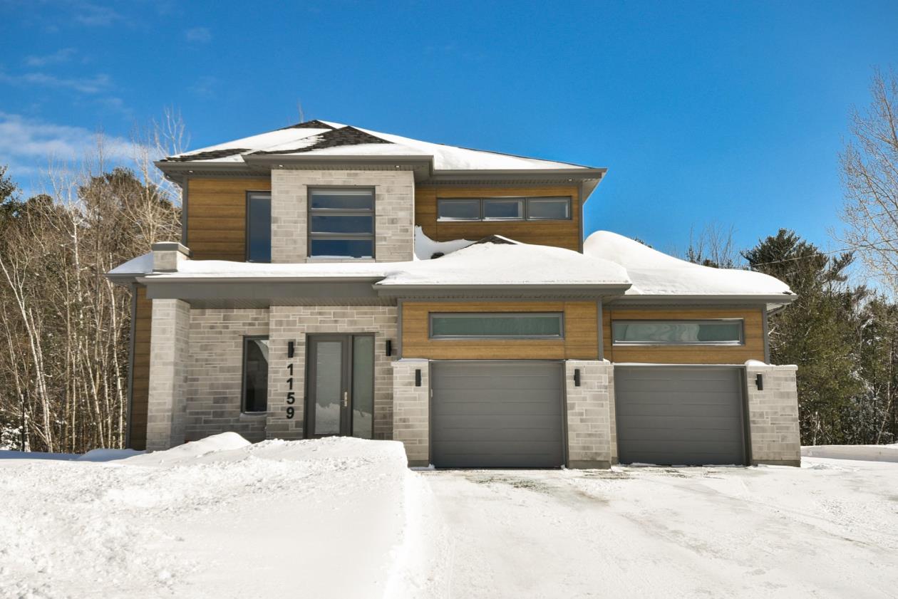 Grande maison contemporaine avec un garage double située sur un terrain dont une partie est boisée