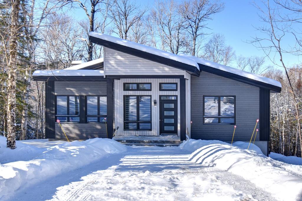 Confort et détente vous attendent dans cette contemporaine baignée de lumière et sise sur un lot boisé d'1 acre 