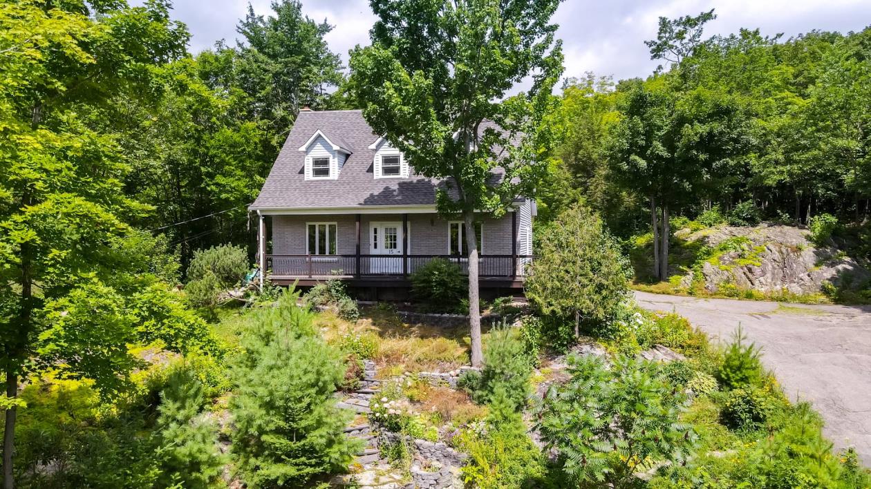 Coquette et invitante demeure de 4 chambres dans un havre de verdure de 82 636 pi²